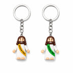 Two keychains with figures wearing sashes that say 'Jesus Loves You' on a white background