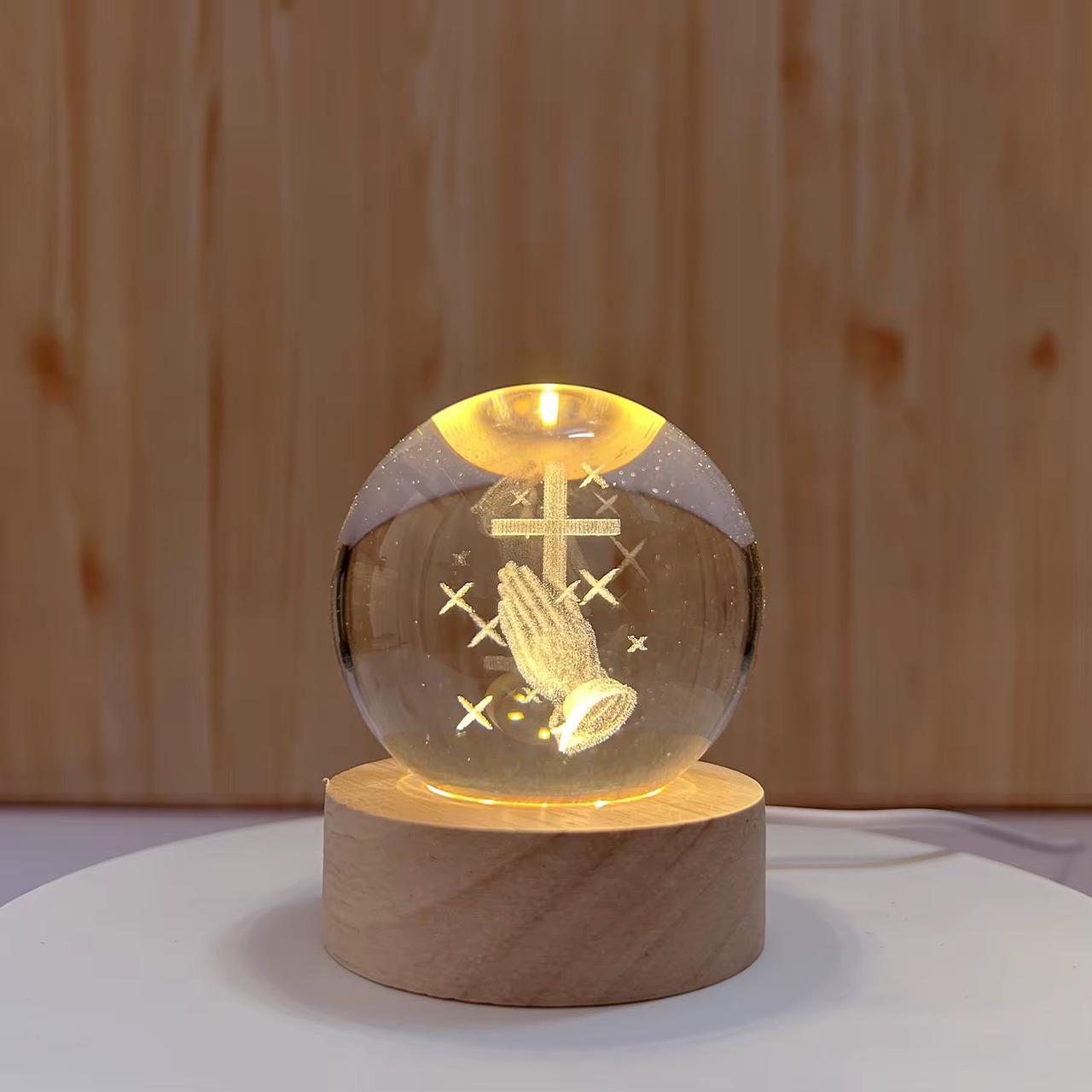 Glass sphere with engraved design on a wooden base against a wooden background