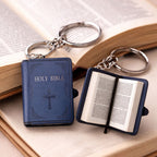 Two blue 'Holy Bible' keychains on an open book